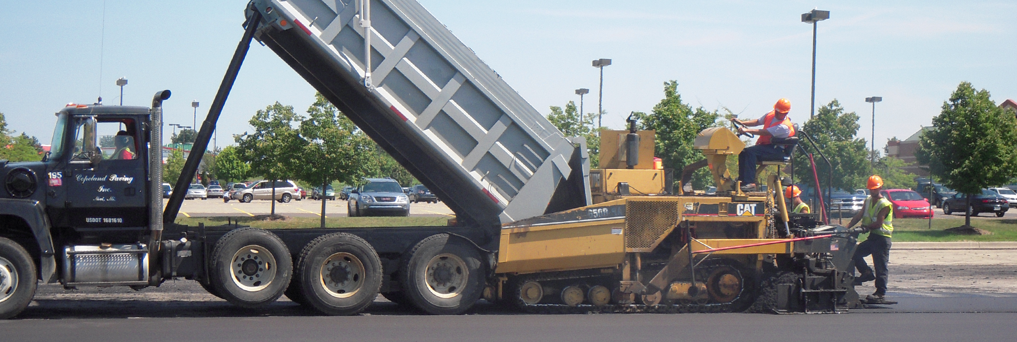 Workers on-site using Copeland Paving dump truck and paving equipment